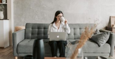 woman drinking coffee while working with laptop