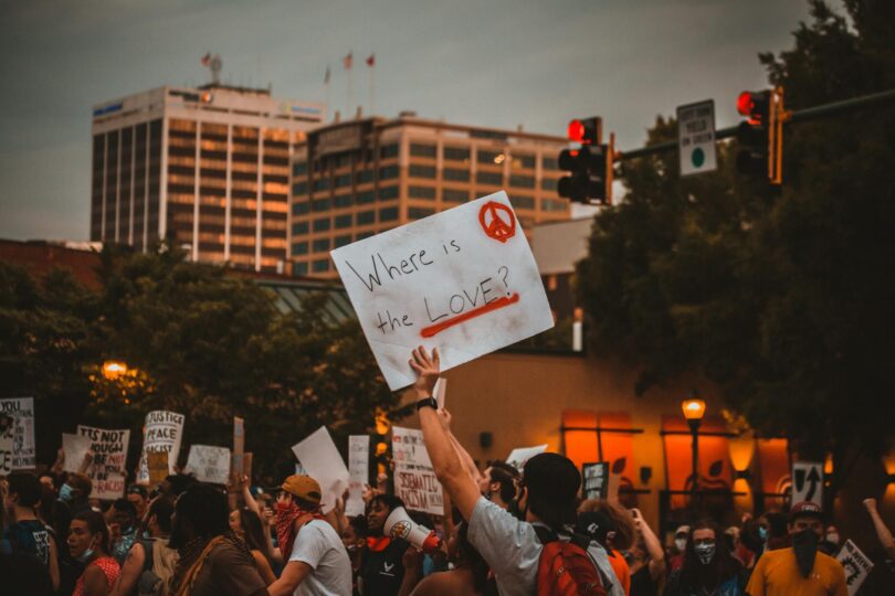 multiracial people with banners protesting on street in evening