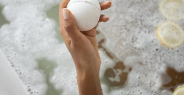 woman with ball of bath salt in bathtub