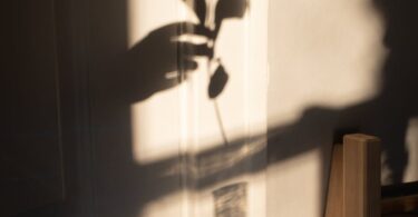 anonymous person putting plant into glass vase