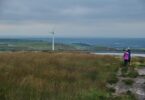 anonymous female travelers looking at windmill in meadow in countryside