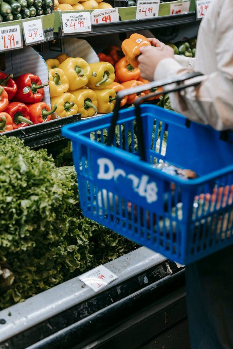 crop person purchasing assorted vegetables in grocery market