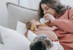 woman feeding infant baby near dog