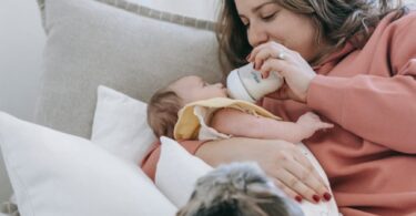 woman feeding infant baby near dog